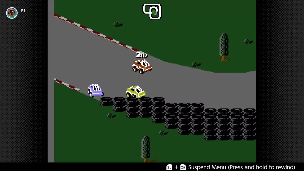 RC Pro-Am 2 screenshot - In the grasslands, vehicles round a bend with a barrier of stacked tires