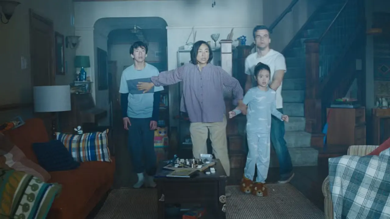An image from The Last House from Netflix. IT shows a family of four standing together in their house in the dark. A bright light outside shocks them.