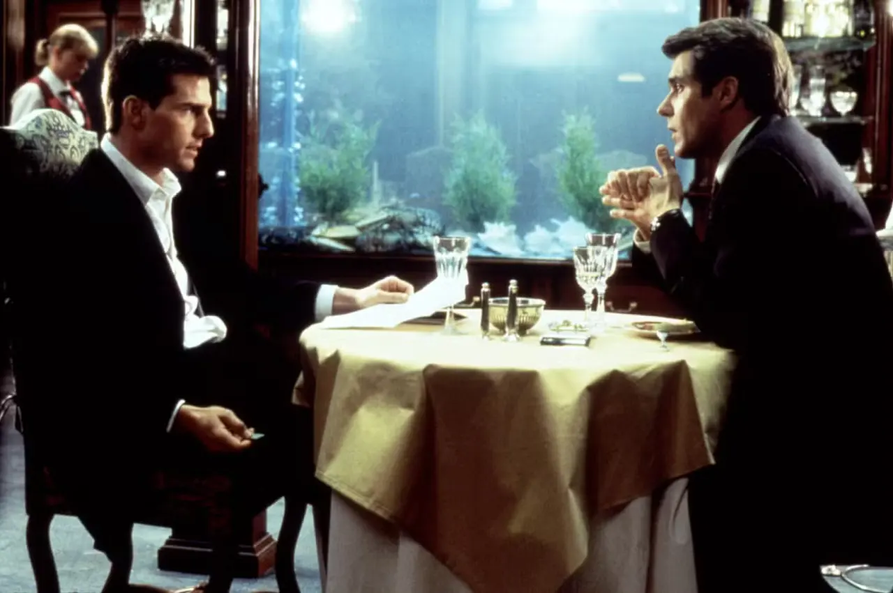Tom Cruise faces Henry Czerny across a restaurant table in front of an aquariam
