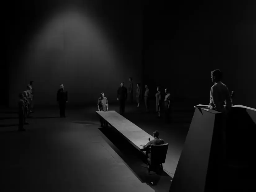 A man stands at the far end of a table awaiting trial in The Twilight Zone episode “The Obsolete Man.”