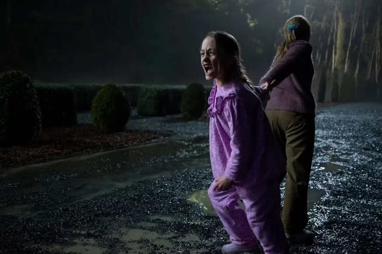 One girl pulls another screaming girl through a big manor garden in The Haunting of Bly Manor