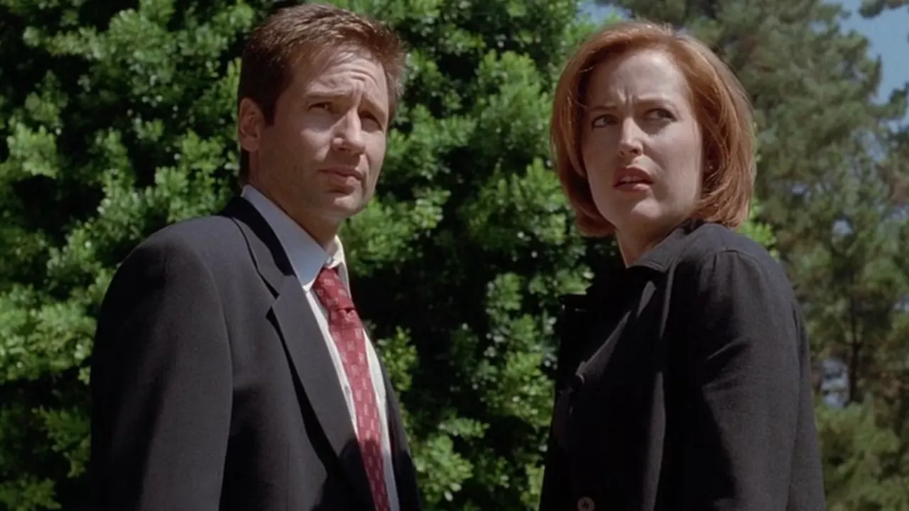 Fox Mulder (David Duchovny) and Dana Scully (Gillian Anderson) stand in front of trees in The X-Files episode Dreamland 2
