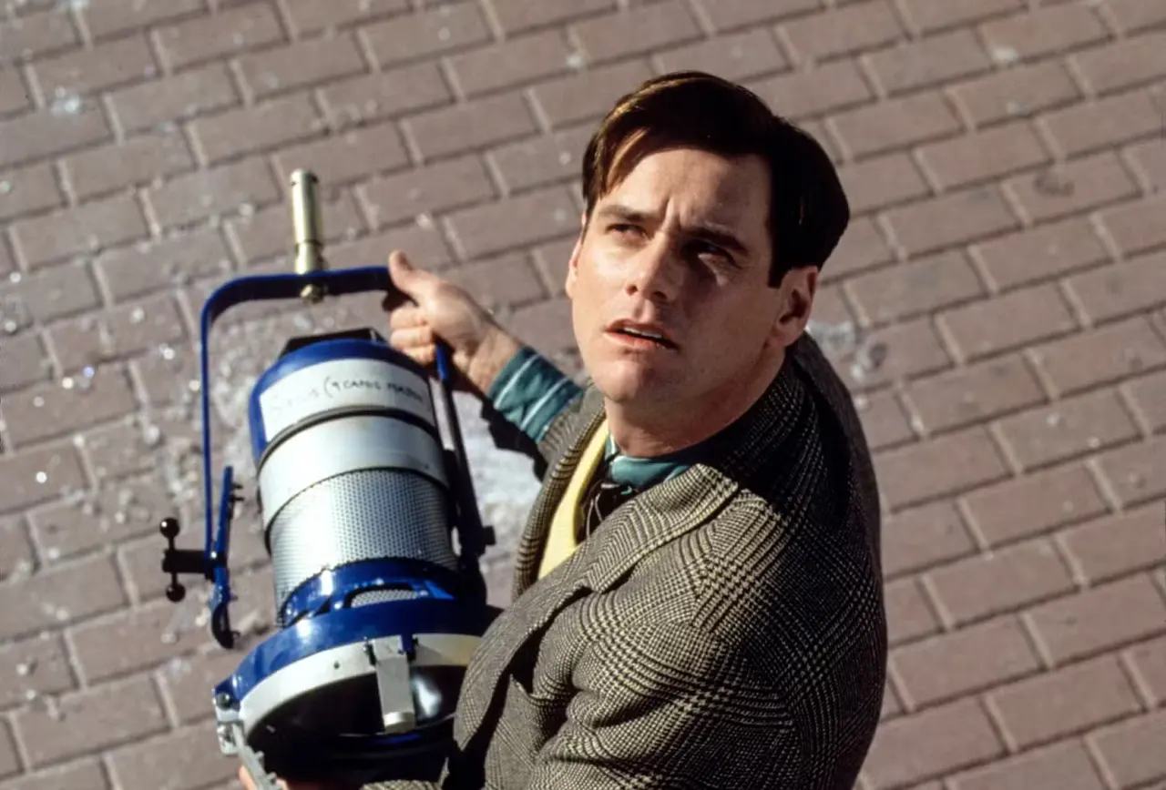 Jim Carrey looks up, confused, while holding a stage light in The Truman Show