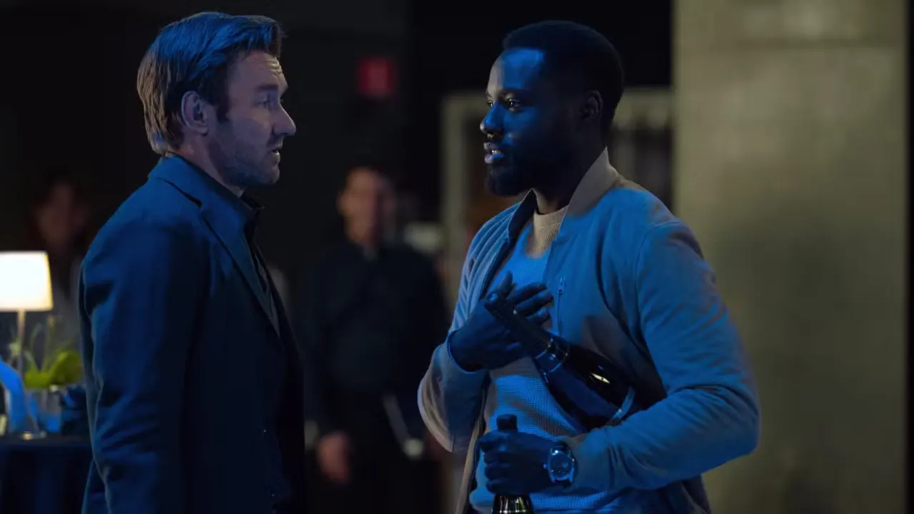 Jason Dessen (Joel Edgerton) talks to Leighton Vance (Dayo Okeniyi), who is carrying two bottles of champagne in Dark Matter season 2